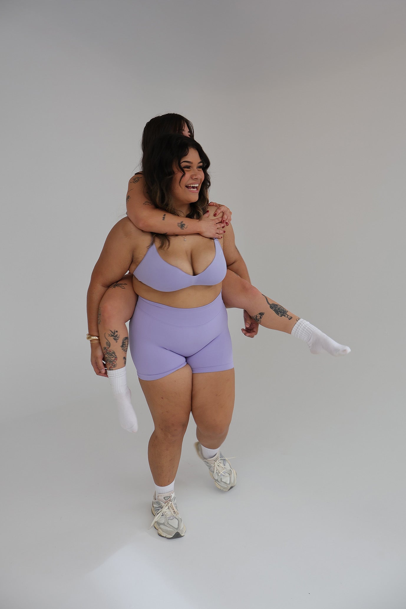 Two people in matching cntor the label activewear outfits posing against a plain background