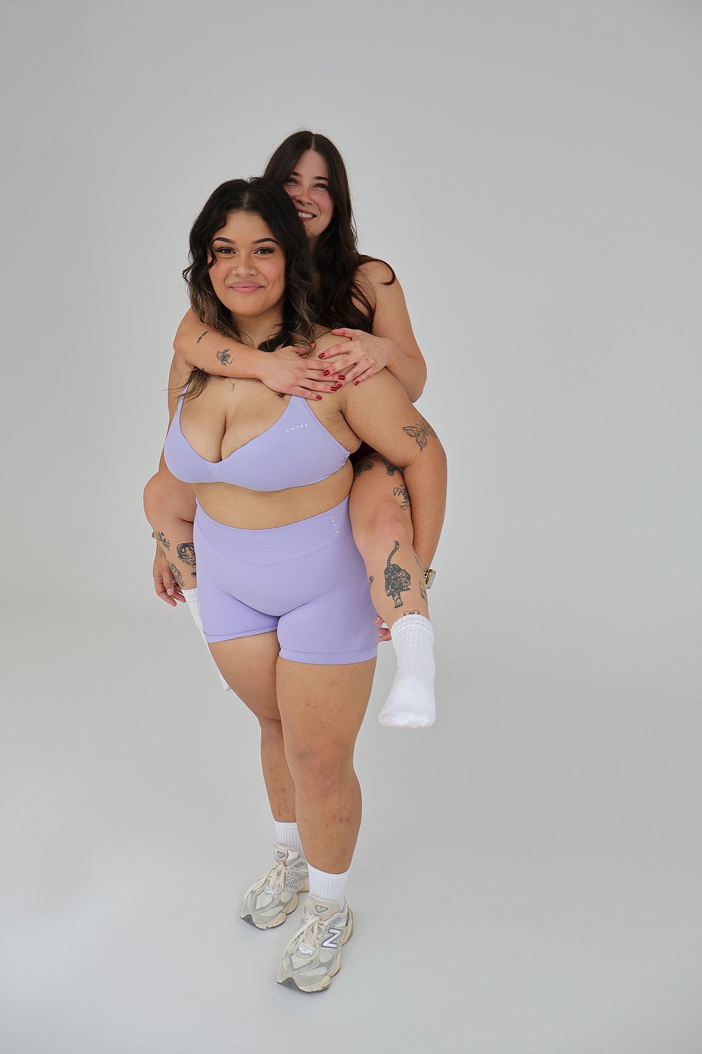 Two women in matching cntor the label activewear outfits posing against a plain background