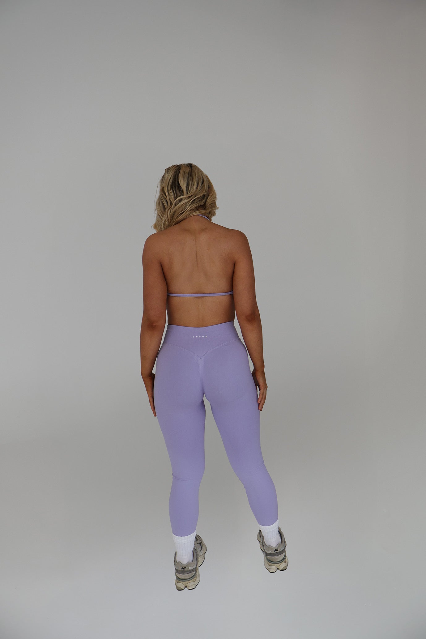 Woman wearing cntor the label activewear with a plain studio background