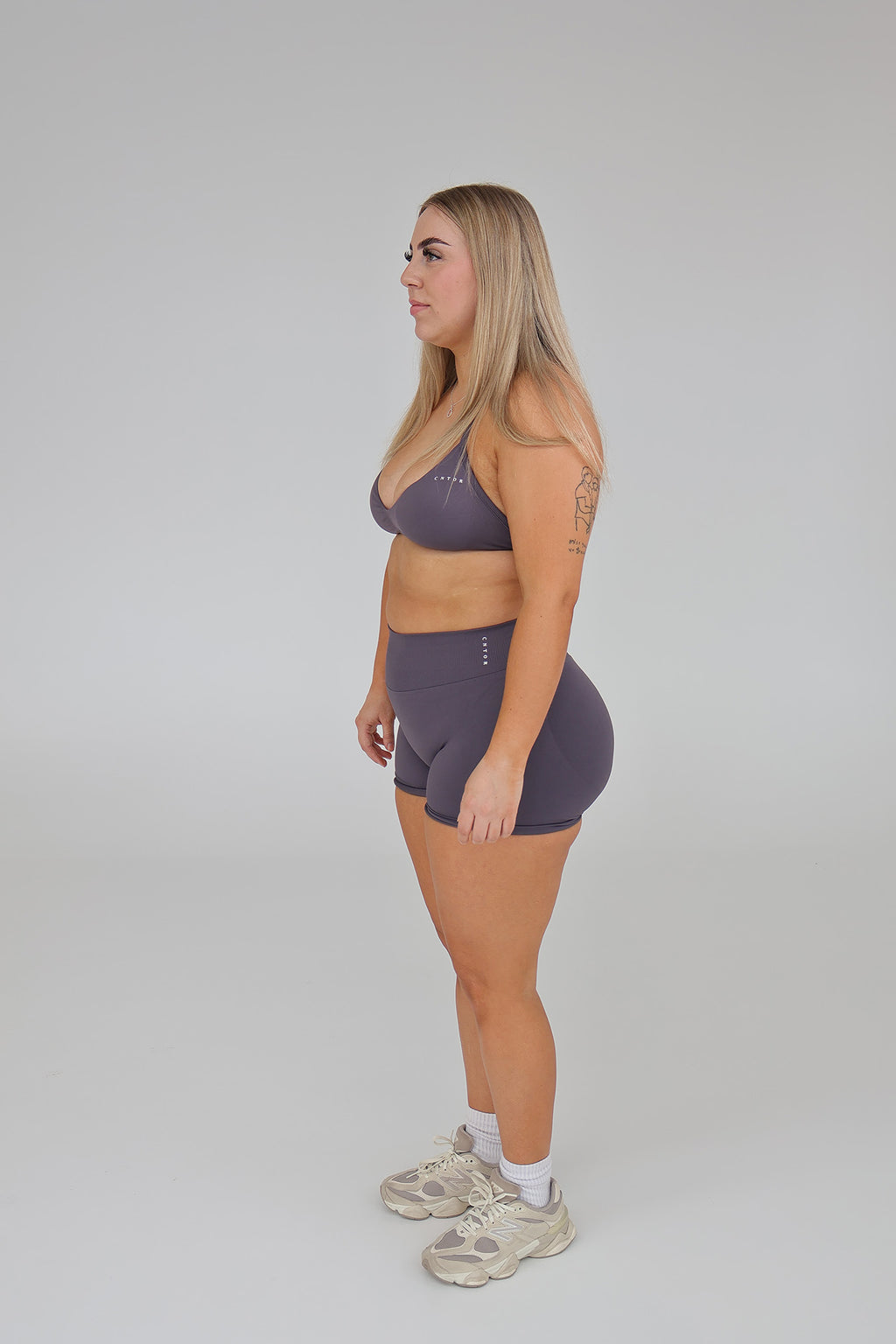 Woman modeling CNTOR seamless storm sports bra and shorts set against a plain studio background.