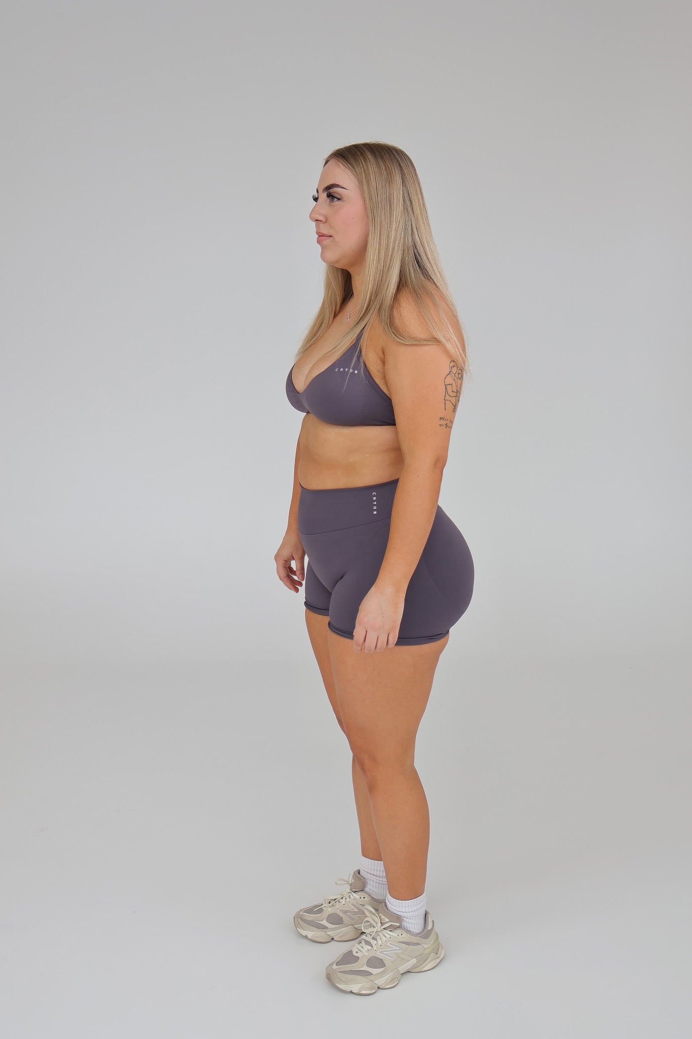 Woman modeling CNTOR seamless storm sports bra and shorts set against a plain studio background.