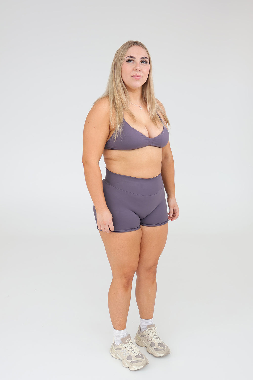 Woman modeling CNTOR seamless storm sports bra and shorts set against a plain studio background.